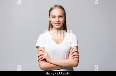 A piena lunghezza Ritratto di una bella donna felice in piedi con le braccia incrociate isolato su uno sfondo bianco. Guardando la fotocamera Foto Stock