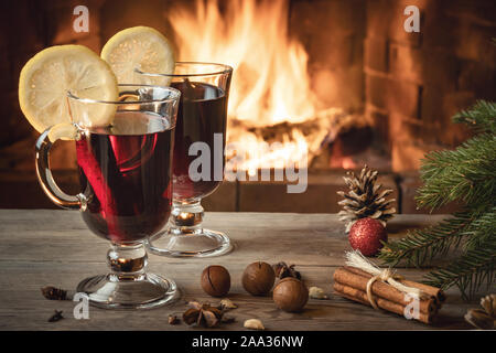 Due bicchieri di vino brulé su un tavolo di legno vicino a un albero di Natale davanti ad un caminetto a. Foto Stock