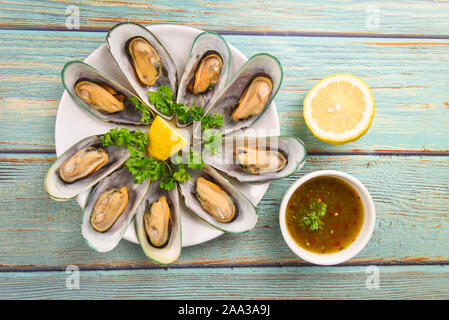 Cozze con erbe aromatiche con limone prezzemolo nella tabella / le cozze al vapore serviti sulla piastra bianca e salsa di deliziosi piatti a base di pesce Foto Stock