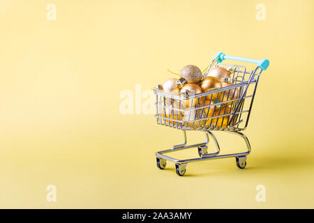 Carrello pieno di regali di Natale luminoso su sfondo giallo Foto Stock