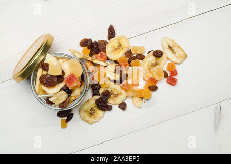 Vista superiore del vasetto di vetro con frutta secca sparsi sul tavolo di legno Foto Stock