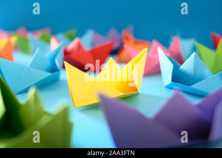 Flotta di origami autentiche barche su sfondo blu Foto Stock