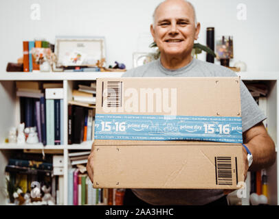 Parigi, Francia - Luglio 10, 2019: sorridendo felice senior man tenendo la perfezione del Amazon cartone con il primo giorno di scotch durante l'e-commerce shopping organo evento Foto Stock