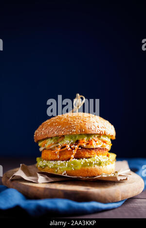 Vegane patata dolce o zucca hamburger con avocado salsa guacamole e carota slaw su sfondo blu scuro con copia spazio per il testo.pasto vegetariano Foto Stock