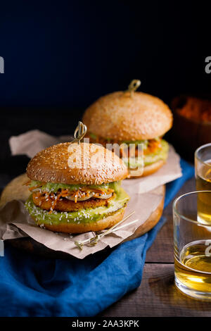 Vegane patata dolce o zucca hamburger con avocado salsa guacamole e carota slaw su sfondo blu scuro con copia spazio per il testo.pasto vegetariano Foto Stock