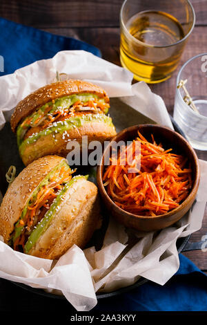 In casa vegane patata dolce o zucca hamburger con avocado salsa guacamole e carota slaw su sfondo in legno close-up top view.pasto vegetariano Foto Stock