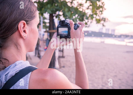 Bella donna di scattare una foto del tramonto. Felice giovane donna con una macchina fotografica e uno zaino. Foto Stock