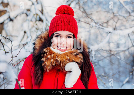 Inverno Ritratto di giovane bella bruna donna che indossa abiti di colore rosso in presenza di neve Foto Stock