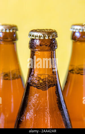 Una bottiglie refrigerate con bevanda su sfondo giallo. La birra in una rugiadosa bottiglia di vetro chiuso con un coperchio. Foto Stock