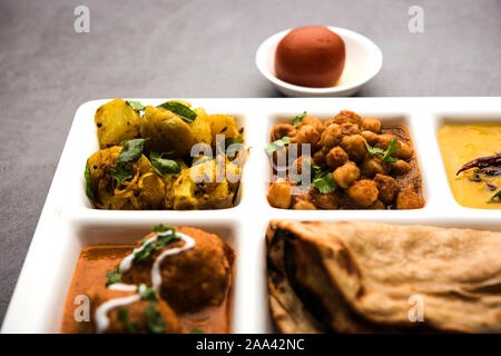 Indian cibo vegetariano Thali o pacco cibo-vassoio con scomparti in cui Malai Kofta, chole, Dal tarka, secco, aloo sabji, chapati e riso con dolce Foto Stock