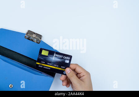 Donna lato estraendo la carta di credito dal blu borsa per il pagamento su uno sfondo bianco. Finanza e concetto di denaro, vista dall'alto, copia spazio per il testo. Foto Stock