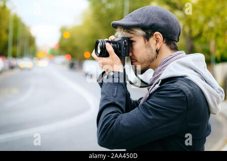 Hipster fotografo tenendo Street foto con la fotocamera Mirrorless Foto Stock