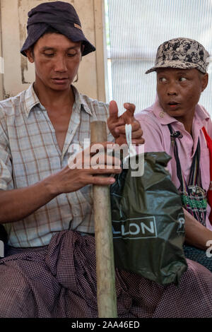 I passeggeri sulla circolare treno locale di Yangon, Myanmar (Birmania) compresi questi due operai della costruzione con i loro cappelli e strumenti Foto Stock