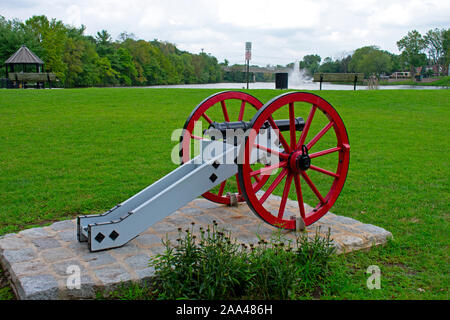 La guerra rivoluzionaria americana cannone con ruote rosse e un nero canna sul display nella parte anteriore di una fontana di acqua al Columbus Park, Piscataway, New Jersey, Foto Stock