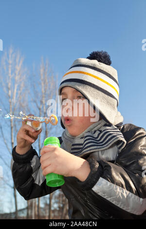 Ragazzo giovane soffia bolle di sapone nel parco Foto Stock