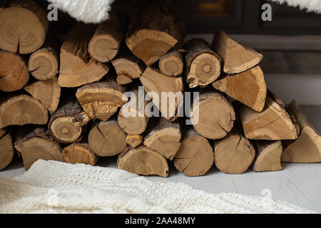 Primo piano della legna da ardere pila posa su coltre bianca sotto il banco di legno. Foto Stock