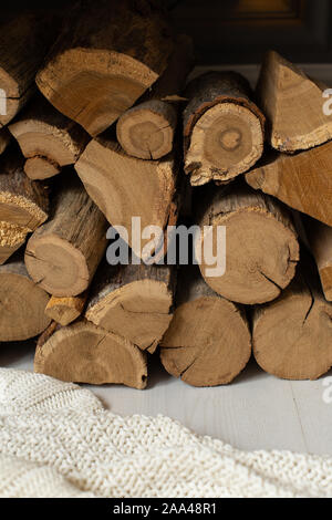 Primo piano della legna da ardere pila posa su coltre bianca sotto il banco di legno. Foto Stock