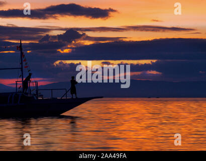 Silhouette di due uomini stavano in piedi sulla nave di prua, Panglao, Bohol, Filippine Foto Stock
