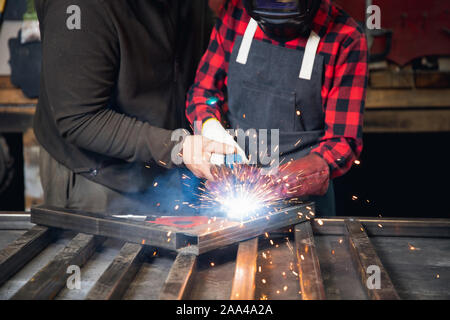 Insegnante maschio master class di saldatura e di lavoro studente della scuola tecnica. Industriale il concetto di istruzione. Foto Stock