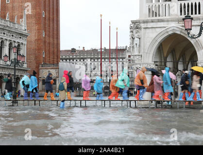 Persone con ombrelloni e impermeabile e speciale plastica soffietti nel giorno di pioggia sul marciapiede in Venezia in Italia Foto Stock