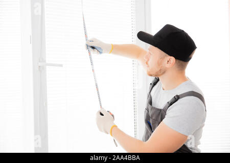 Master misure lavoratore upvc finestra con righello, il processo di installazione. Foto Stock