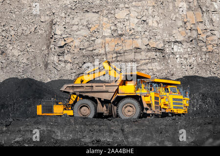 Grande giallo carrello minerario antracite con carico si sposta fossa aperta della miniera di carbone. Foto Stock