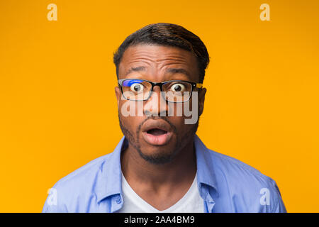 Sorpreso African American Guy guardando la fotocamera in posa, sfondo giallo Foto Stock