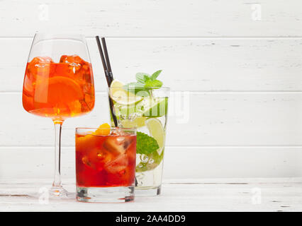 Tre cocktail classico bicchieri sul tavolo di legno. Negroni, aperol spritz e mojito. Con spazio di copia Foto Stock