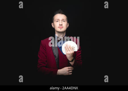 Illusionista uomo mostra la ventola di carte da gioco in mano su sfondo nero. Foto Stock