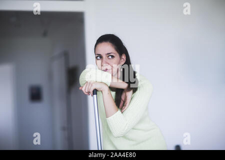 Frustrati donna appoggiato su di una scopa Foto Stock