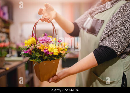 Fioraio ragazza detiene il mazzo di fiori rose rosa e giallo crisantemi in confezione regalo. Foto Stock