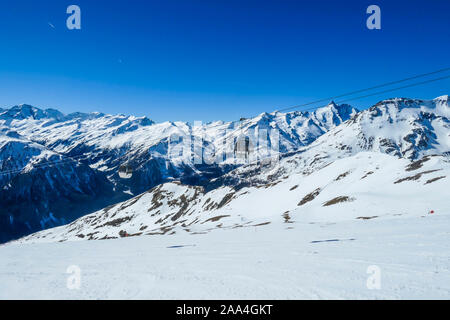 Due gondole andando su e giù sopra la neve montagne tappata. Le gondole sono mobili su funi spesse appeso molto alta. Nella parte posteriore vi sono alte Alpi. Foto Stock