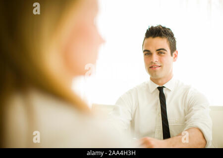 Coppia giovane seduto e parlando Foto Stock