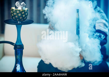 L'uomo detiene il narghilè, mano in fumo shisha. Foto Stock