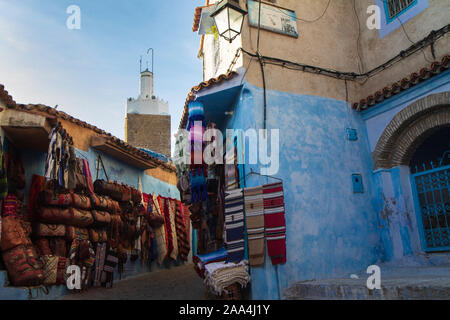 Vista di un angolo di Chefchauen, 'la perla blu' nelle montagne del Marocco. Appesi alle pareti vi sono elementi tipici che sono in vendita in città Foto Stock