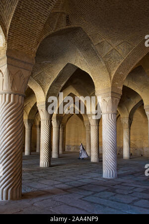 Donna in abiti tradizionali a piedi attraverso la sala di preghiera della moschea Vakil, Shiraz, Iran Foto Stock