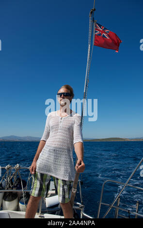 Uomo in piedi sul ponte la sterzatura di un yacht, Sardegna, Italia Foto Stock