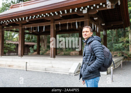 Tokyo, Giappone Meiji con architettura giovane turista uomo in piedi da purificazione fontana edificio pagoda Foto Stock