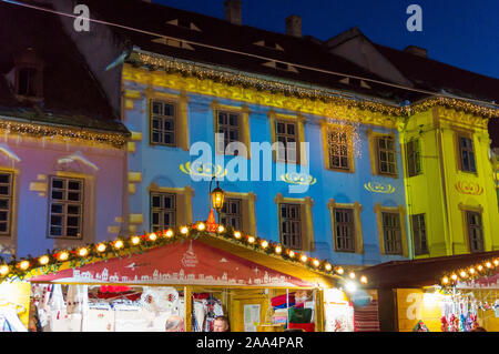 Mercatino di Natale a Sibiu in Transilvania. Inverno magico night immagine con i turisti e le decorazioni di Natale in Piazza Grande di città medievale Sibiu Foto Stock