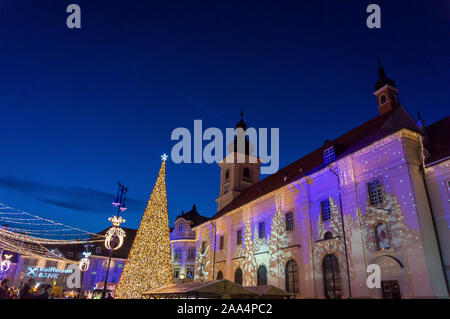 Mercatino di Natale a Sibiu in Transilvania. Inverno magico night immagine con i turisti e le decorazioni di Natale in Piazza Grande di città medievale Sibiu Foto Stock