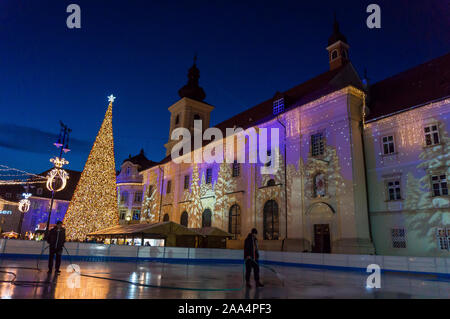 Mercatino di Natale a Sibiu in Transilvania. Inverno magico night immagine con i turisti e le decorazioni di Natale in Piazza Grande di città medievale Sibiu Foto Stock