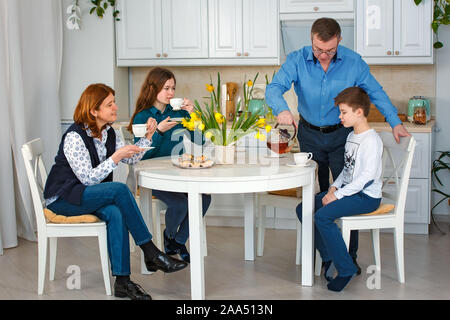 Sessione fotografica - famiglia amichevole. Il tè del mattino. Padre versa il tè. Foto Stock