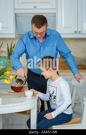 Sessione fotografica - famiglia amichevole. Il tè del mattino. Padre versa il tè. Foto Stock