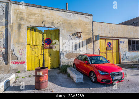 Red Audi berlina parcheggiato di fianco a consumato in legno porta di garage Foto Stock