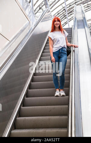 Ragazza va giù sulla scala mobile ringhiera di contenimento Foto Stock