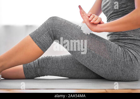 Ragazza con sfera di massaggio nelle sue mani seduto sul tappeto in palestra durante il giorno Foto Stock