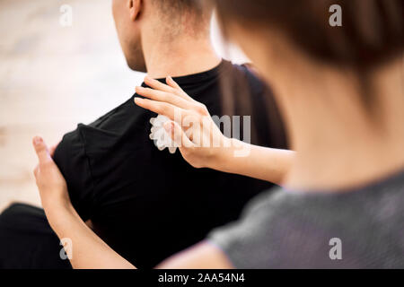 Donna facendo massaggio alla schiena per uomo con sfera di massaggio in camera, vicino fino Foto Stock