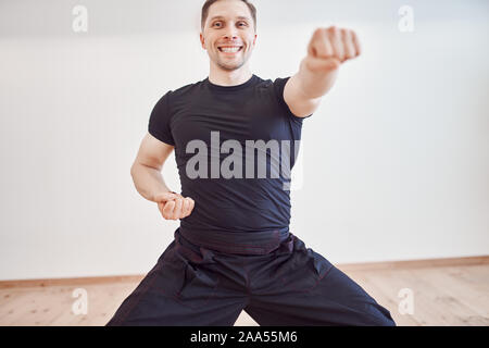 Giovani brunette in tuta nera è impegnato nelle arti marziali in hall durante il giorno Foto Stock