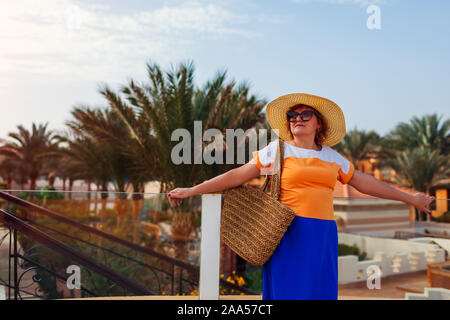 Senior donna camminando sul territorio di hotel in Egitto. Estate vacanza tropicale. Elegante look alla moda Foto Stock