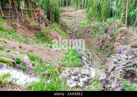 Cascata cascata elevato angolo vista sulla pista di ghiaccio al lago vicino Silverton, Colorado in agosto 2019 mattina d'estate con la valanga di detriti che coprono i registri di rive Foto Stock